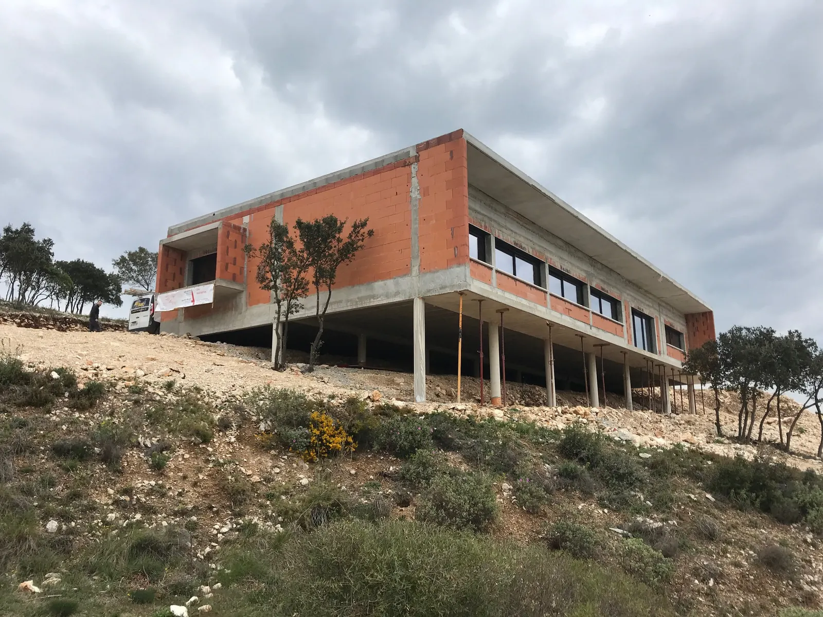 Siège social AT — Un bâtiment de bureaux posé dans la garrigue, sur pilotis et toiture-terrasse.