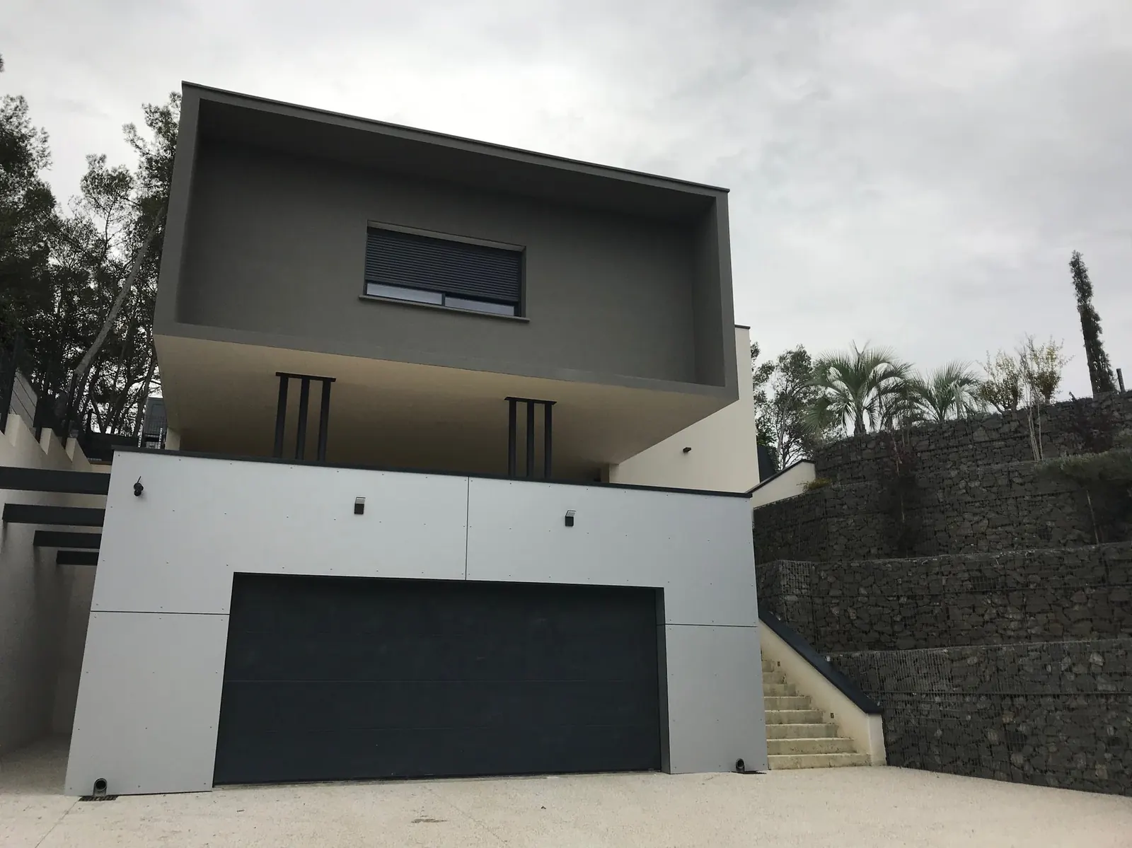 Villa G — Une maison en strates sur un terrain en pente, entre façade minérale et terrasse sur piscine.